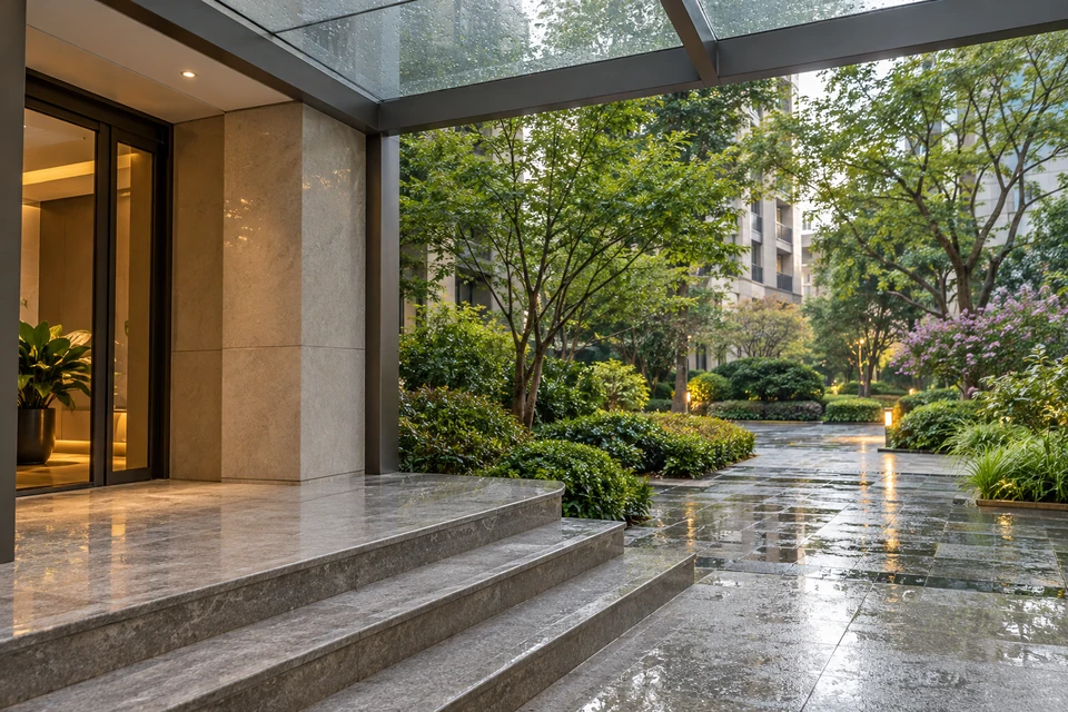 住宅空间灵感：住宅楼入口前简洁的玻璃雨棚覆盖干燥石阶，外侧雨后绿树与水珠泛着自然光。